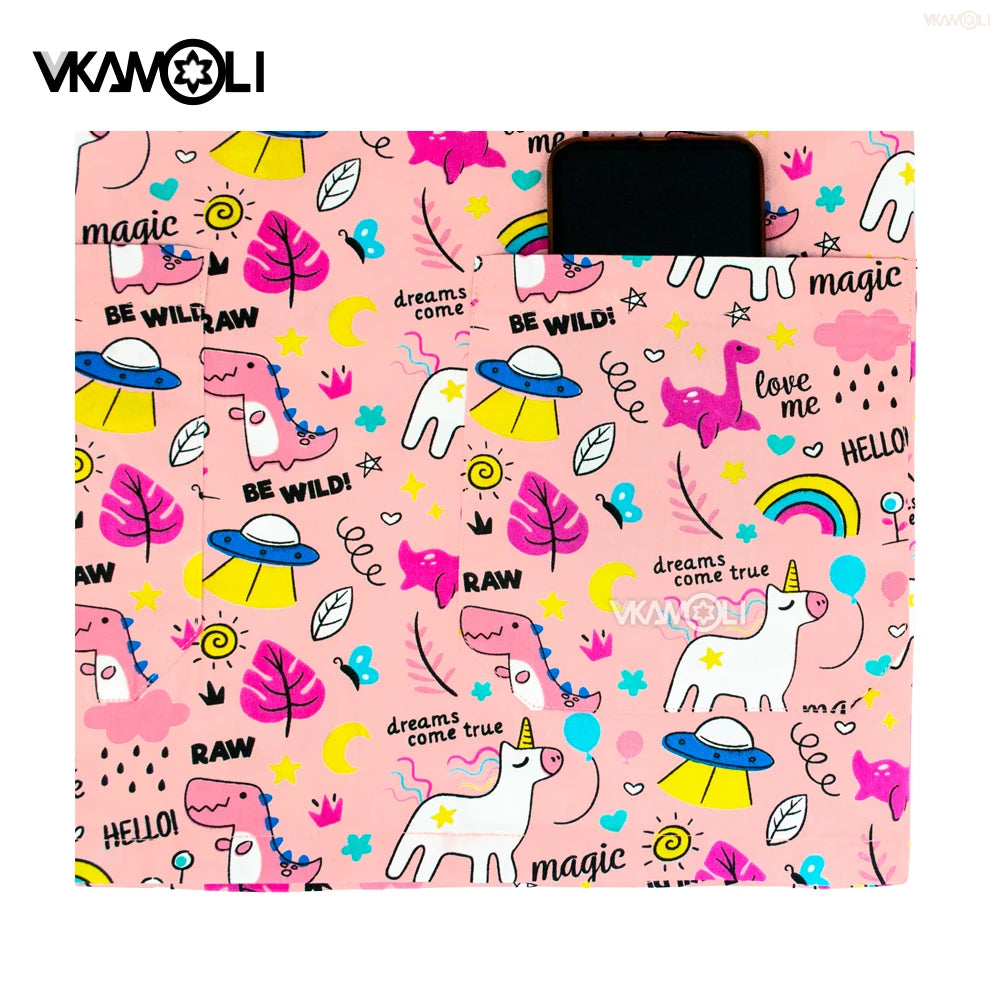 Cartoon print scrub top featuring whimsical unicorns, dinosaurs, and colorful designs on a pink background.