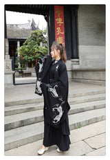 Woman wearing a Han Dynasty couple costume in black with dragon embroidery, posing outdoors near a traditional building.