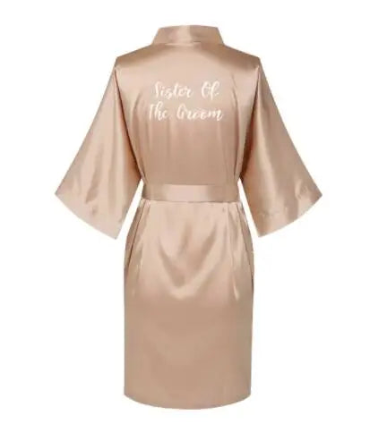 Back view of a satin rose gold bridesmaid robe with 'Sister Of The Groom' text in elegant font.