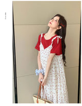 Model wearing a floral two-piece maternity dress with a red top and white skirt, showcasing a stylish summer look.