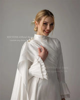 Muslim satin wedding dress featuring pearl accents, high neck, and long sleeves in elegant floor-length design.