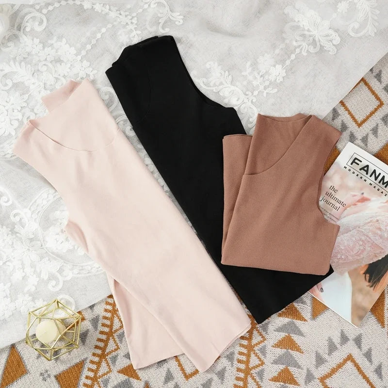 Three HeatHold™ thermal slim inner vests in pink, brown, and black laid out on a stylish background with a magazine.