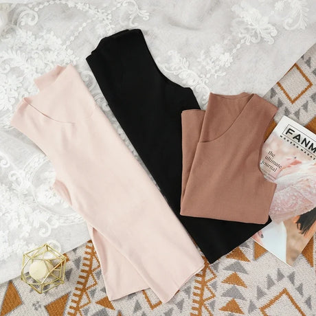 Three HeatHold™ thermal slim inner vests in pink, brown, and black laid out on a stylish background with a magazine.