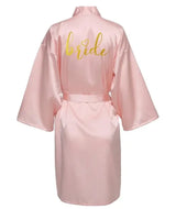Pink satin bridal robe featuring gold 'bride' lettering, ideal for wedding celebrations and bridal parties.