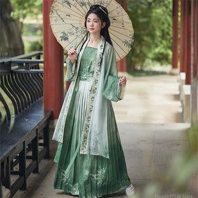Elegant Women's Hanfu cosplay in green dress with floral details, styled with a parasol in a serene outdoor setting.