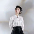 Woman in traditional Hanfu outfit featuring a white top and black skirt, highlighting elegance and cultural heritage.