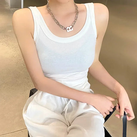 Model wearing a white ribbed sleeveless tank top paired with casual joggers and accessories, showcasing streetwear style.