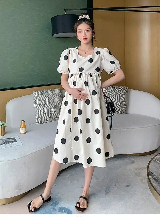 Model wearing a polka dot loose maternity dress in a stylish indoor setting, showcasing a mid-calf design for summer.