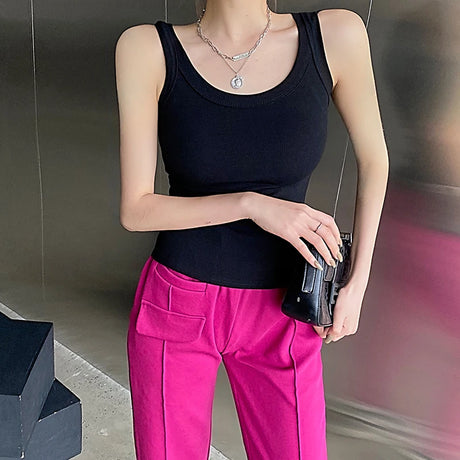 Model wearing RetroRib™ 90s Vintage Ribbed Tank, black sleeveless crop top paired with pink pants, showcasing trendy streetwear style.