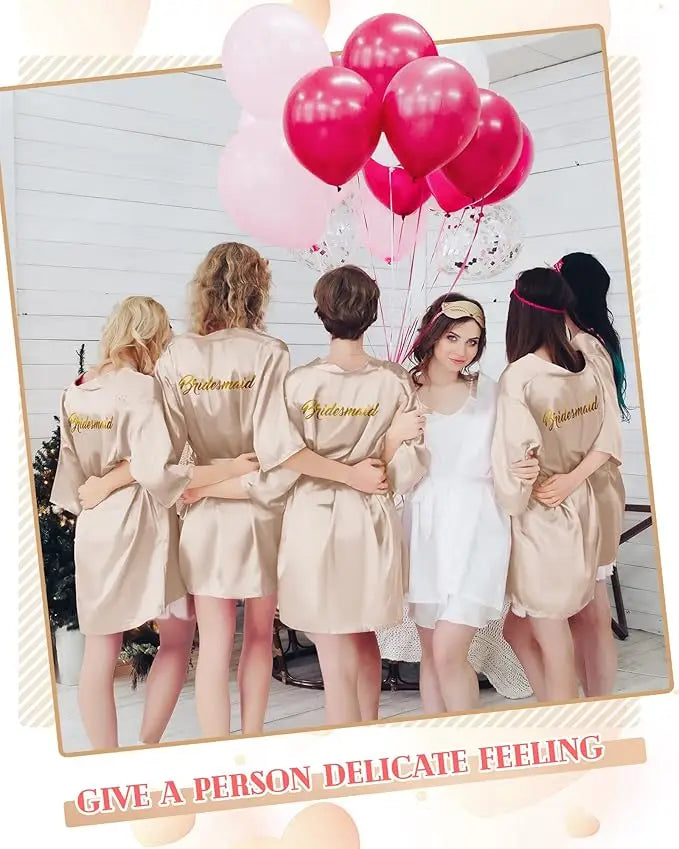 Bridesmaids in satin kimono robes with gold embroidery, holding pink balloons at a wedding shower.