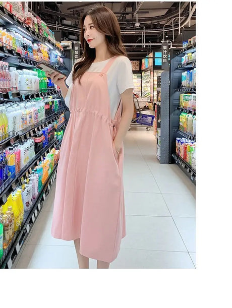 Woman in a pink loose fit maternity dress shopping in a grocery store aisle.