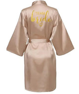 Gold satin bride robe with 'TEAM bride' printed in glitter, knee-length, perfect for bridal parties.