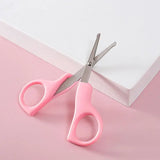 Pink children's scissors on a pink background, ideal for crafting and safe for kids.