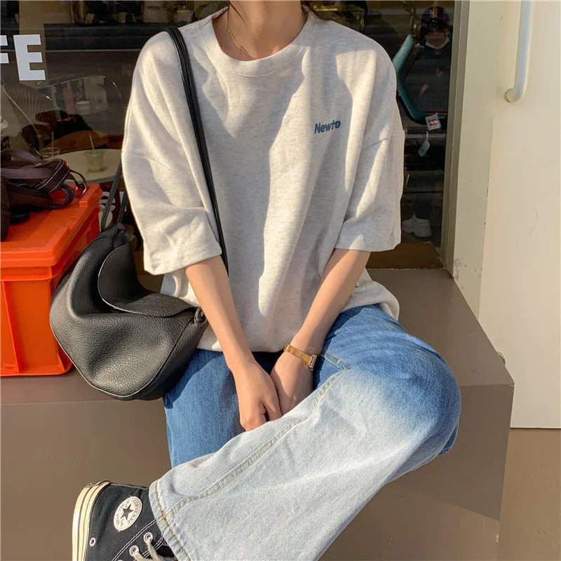 Oversized Harajuku streetwear tee in grey on a model, paired with baggy jeans and a chic handbag.