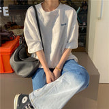 Oversized Harajuku streetwear tee in grey on a model, paired with baggy jeans and a chic handbag.