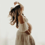 Pregnant woman in soft, flowing boho maternity dress, posing gracefully in a light-filled space for a photoshoot.