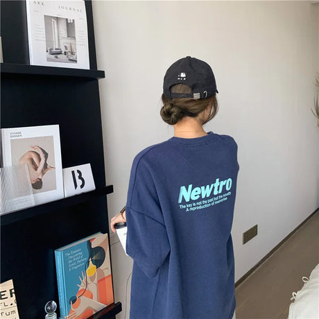 Oversized navy Harajuku tee with 'Newtro' print, styled casually with a cap, perfect for streetwear enthusiasts.