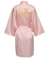 Pink satin robe for brides with 'TEAM bride' in glittery gold lettering on the back.