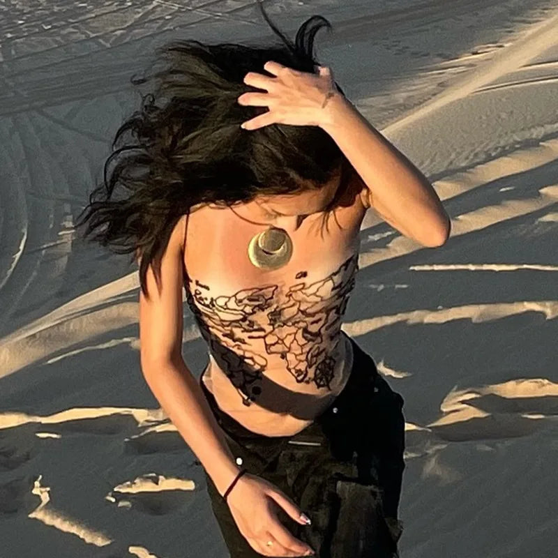Woman wearing a sleeveless mesh backless tube crop tank top in a sandy landscape, styled with a necklace.