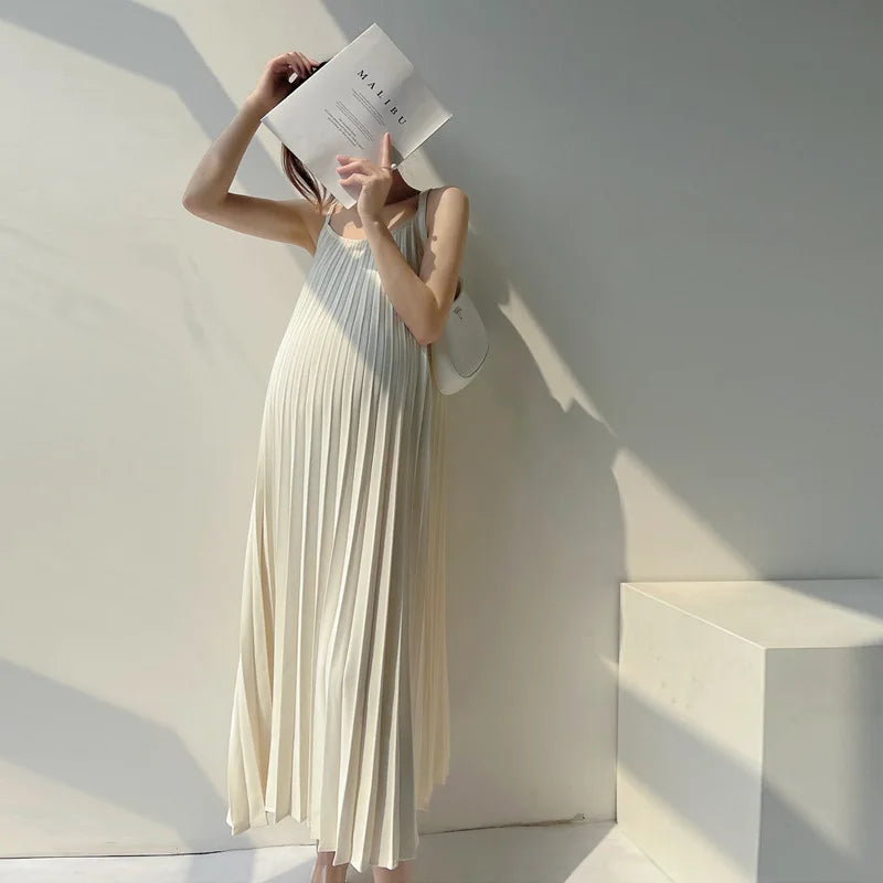 Pleated chiffon maternity dress in natural color, mid-calf length, model holding a magazine, perfect for summer.
