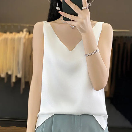 Woman wearing a white satin V-neck camisole top, showcasing summer style and comfort.