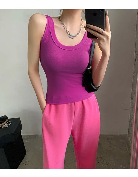 Model wearing a sleeveless pink ribbed tank top with matching pink pants in a stylish pose.