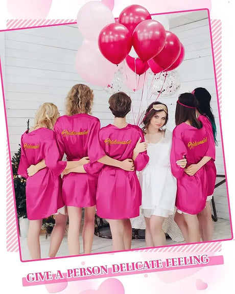Group of women in pink satin kimono robes with balloons at a wedding shower, showcasing friendship and celebration.