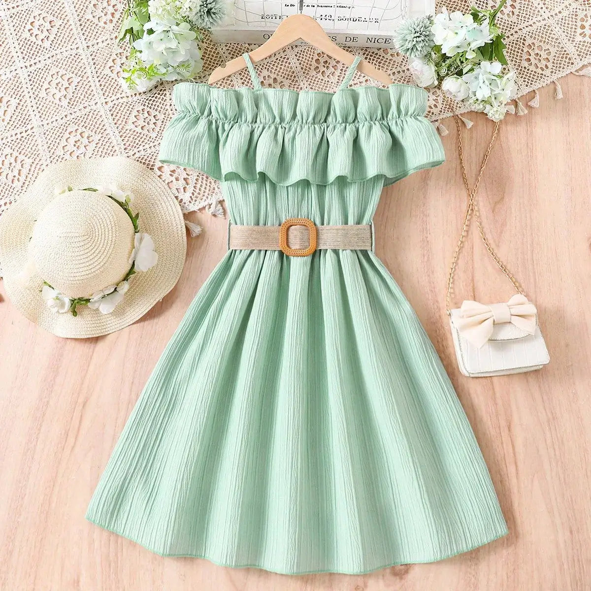 Mint green girls casual dress with one-line shoulder straps and ruffled neckline, styled with a belt and summer accessories.