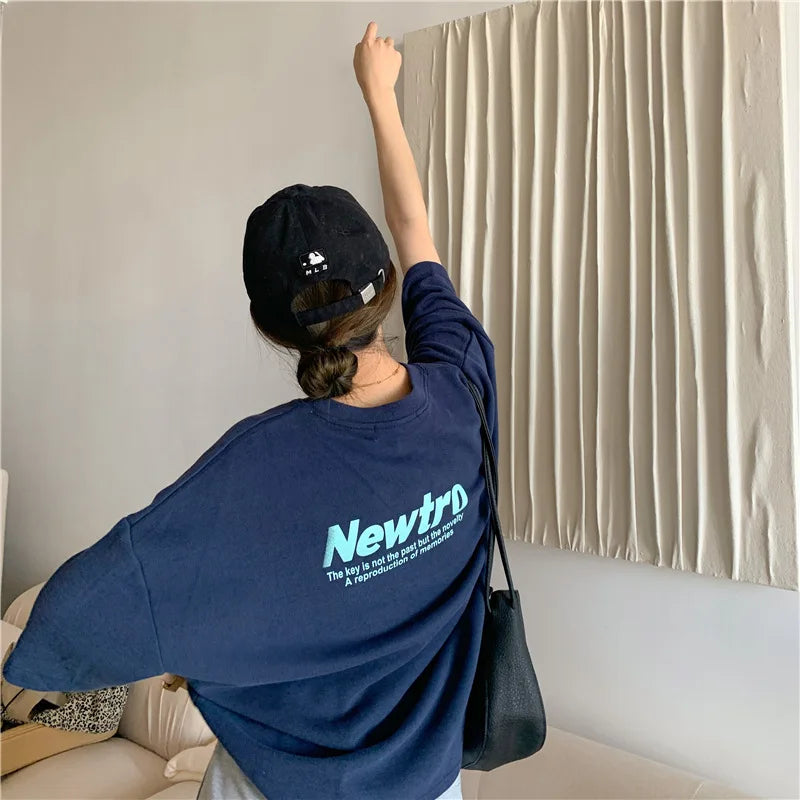 Young woman wearing an oversized navy Harajuku streetwear tee with a trendy cap, showcasing a casual street style.