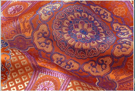 Vibrant Mongolian ethnic fabric featuring intricate patterns in rich orange and purple hues.