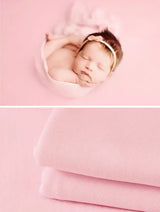 Newborn soft wrap blanket in pastel pink, perfect for baby photography and cozy cuddles, featuring a sleepy baby and soft fabric.