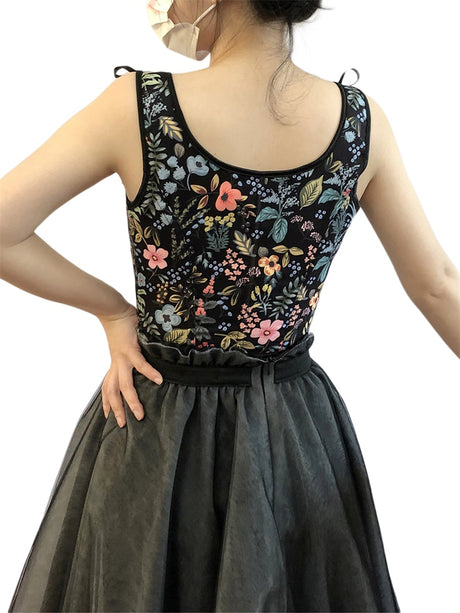 Back view of a woman wearing a floral print cropped camisole with a black skirt.