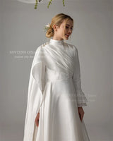 Elegant Muslim satin wedding dress with high neck and long sleeves, embellished with pearls and draped details.