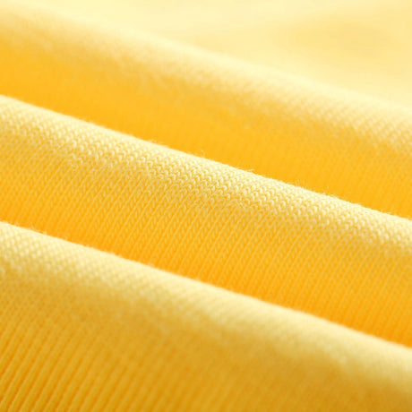 Close-up of soft yellow cotton fabric, showcasing texture and quality for clothing design.