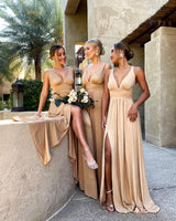 Three women in elegant backless bridesmaid evening gowns posing together outdoors with floral decor.