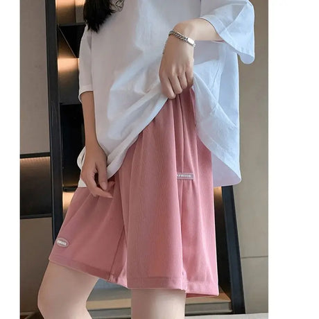 Model wearing loose pink maternity shorts paired with a white oversized shirt, perfect for summer casual style.