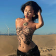 Model wearing a sleeveless tube top with a world map design, posing in a desert landscape with wind turbines.