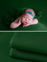 Newborn sleeping on a green soft wrap blanket with a headband, perfect for photography accessories.