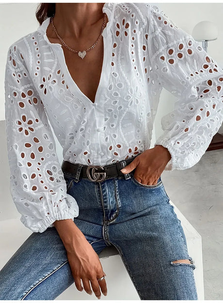 Woman modeling the LaceWhisper™ white lace shirt with long sleeves and v-neck, paired with denim jeans.