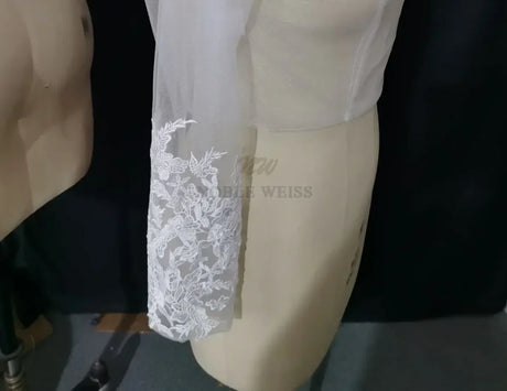 Lace bridal bolero with long sleeve and floral appliqué details, perfect as a wedding wrap by Noble Weiss.
