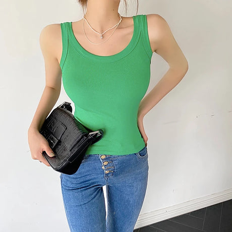 Model wearing a green sleeveless ribbed tank top paired with blue jeans, showcasing a stylish streetwear look.