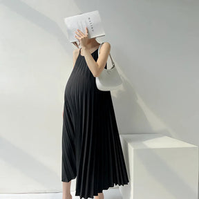 Pleated chiffon maternity dress in black, mid-calf length, worn by pregnant woman, featuring a stylish design.