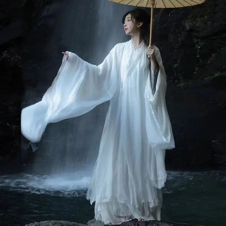 Model in elegant white Hanfu costume with an umbrella near a waterfall, representing Tang Dynasty aesthetics.