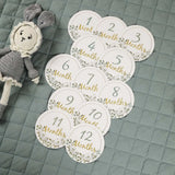 Memorial milestone cards for newborns featuring numbers 1-12 with floral design on a quilted surface.