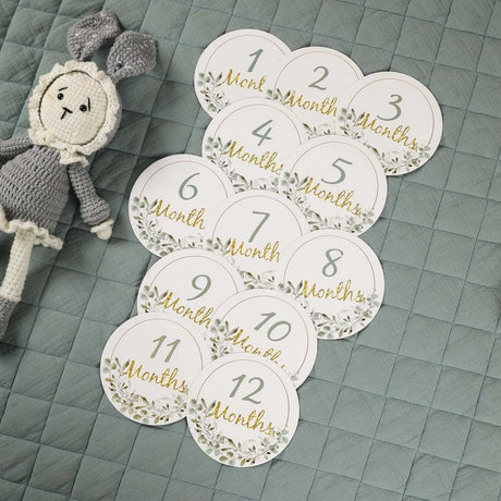 Memorial milestone cards for newborns featuring numbers 1-12 with floral design on a quilted surface.