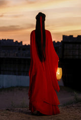 Woman in a red Hanfu dress holding a lantern, against a sunset backdrop, showcasing traditional Chinese cosplay attire.