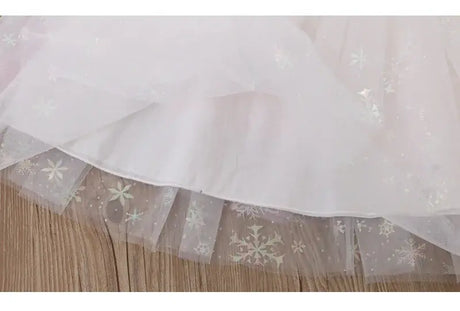 Close-up of white tulle fabric with floral patterns and a sparkling finish, ideal for summer dresses.