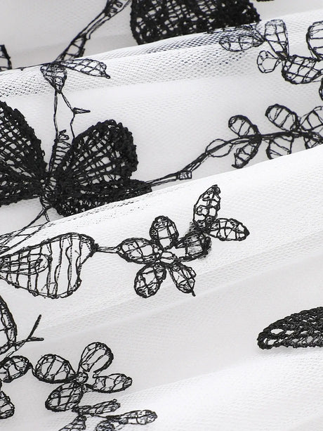Close-up of intricate black lace pattern on white fabric, featuring flowers and butterfly designs.