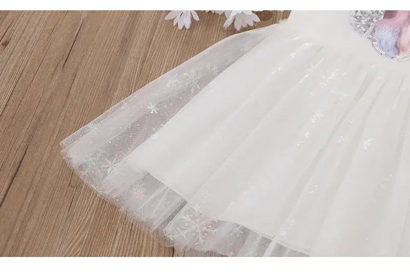 Close-up of a girl's knee-length summer dress with a shimmering tulle skirt and floral details.