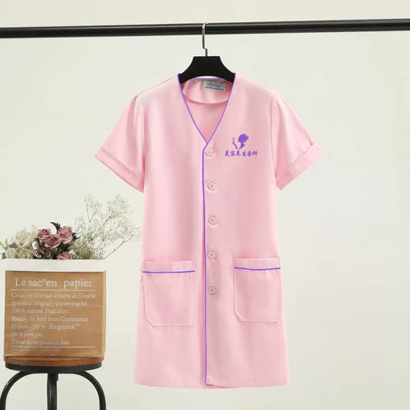 Custom logo beauty uniform in pink, short sleeve lab coat with pockets, ideal for salons and medical settings.